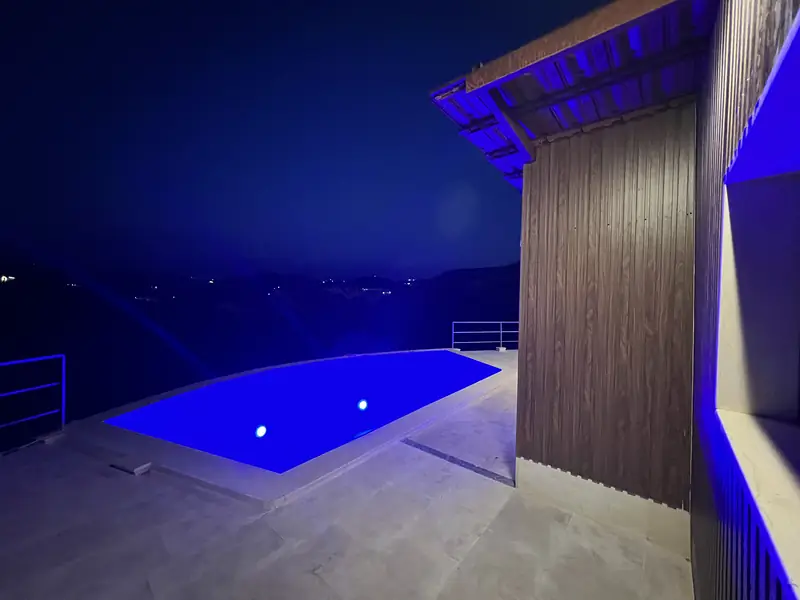 The infinity pool lit blue after dark, above the valley